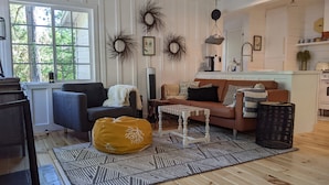 A cozy living room with a brown leather sofa, a gray armchair, a yellow bean bag, and a patterned rug. - Charming Fox Cottage w/ Wood Burning Fireplace (Idyllwild-Pine Cove)