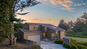 Une maison moderne à deux étages, dotée d’un garage, d’une allée couverte et d’un jardin bien entretenu.
