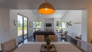 Un espace repas moderne avec une grande table, des chaises et un vase central.