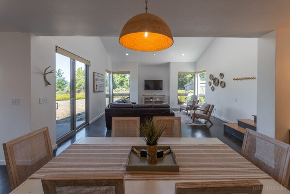 A modern dining area with a large table, chairs, and a central vase.
