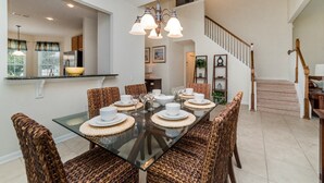 A dining area with a glass table, wicker chairs, and a staircase in the background. - New Listing! Windsor Hills Resort, 3mi to Disney & 12mi to Universal - GRH438891 (Kissimmee)