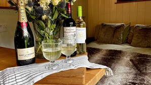 Una mesa de madera con una botella de Moët & Chandon, dos copas, un jarrón de flores y una botella de vino Chateau de Villeclaire.