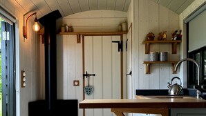 Una cocina rústica con vigas de madera, estufa empotrada y una barra de madera.
