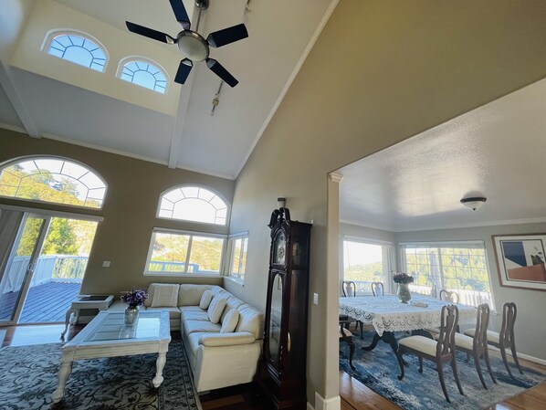 Un vaste espace de vie comprenant un ventilateur de plafond, un canapé, une table basse et un coin repas avec une table et des chaises.