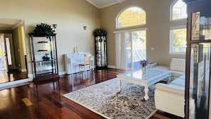 Un salón espacioso con suelos de madera, un sofá blanco, una mesa de centro de vidrio y un ventanal que ofrece luz natural.