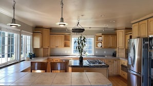 Una cocina amplia con armarios de madera, un refrigerador de acero inoxidable y una isla central con estufa a gas.