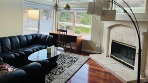 Un salón amplio con un sofá de cuero negro, una mesa de centro de vidrio y una chimenea.