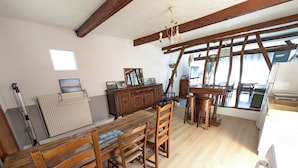 A spacious room with a wooden dining table, chairs, a wooden cabinet, and a window with a view.