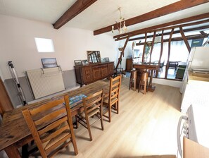 Una habitación amplia con una mesa de comedor de madera, sillas, un armario de madera y una ventana con vistas.