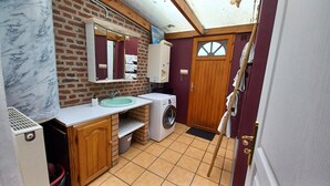 A compact bathroom with a marble sink, a washing machine, and a mirror above the sink.
