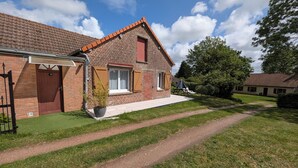 A brick house with a red-tiled roof, a front door, and a small garden area with a paved path.