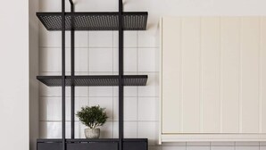 Une cuisine dotée d’un plan de travail noir, de meubles blancs, d’un évier blanc et d’une étagère suspendue agrémentée d’une plante.