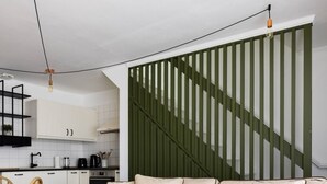 Un salon moderne avec un canapé beige, une table à manger avec des chaises, et une cuisine en arrière-plan.
