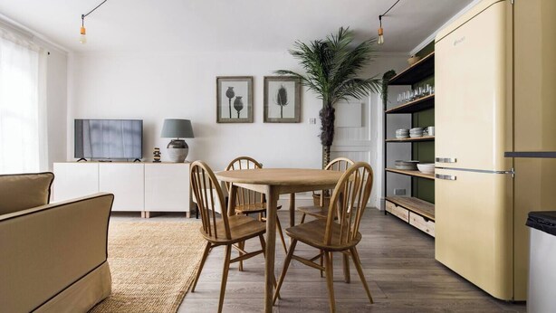 Une cuisine moderne avec un coin repas, comprenant une table et des chaises en bois, un téléviseur et un réfrigérateur.