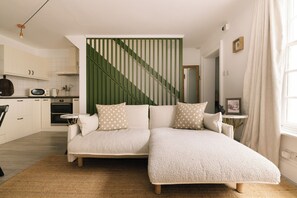 Un salon moderne avec un canapé, un coin cuisine et un escalier.