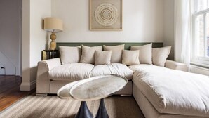 A modern living room with a sectional sofa, a small round table, and a wall-mounted lamp.