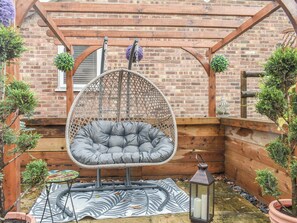 A wooden pergola with a hanging chair, a lantern, and potted plants.