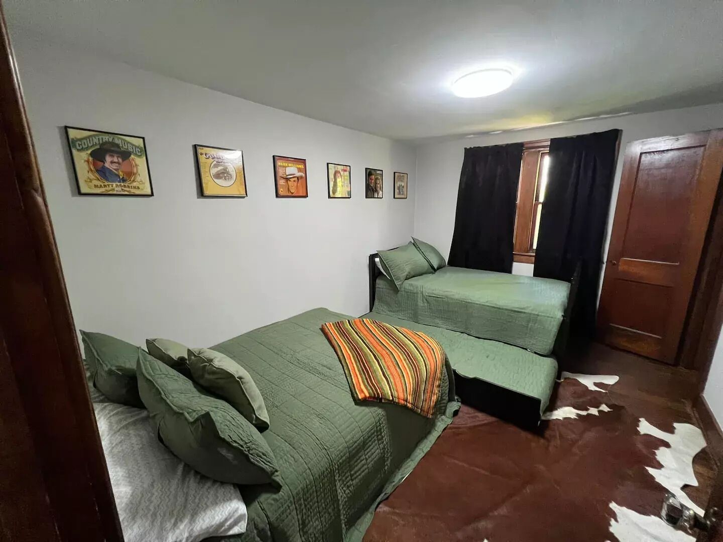 Ein Zimmer mit zwei Einzelbetten, einer Holztür und einem Kuhfellteppich.