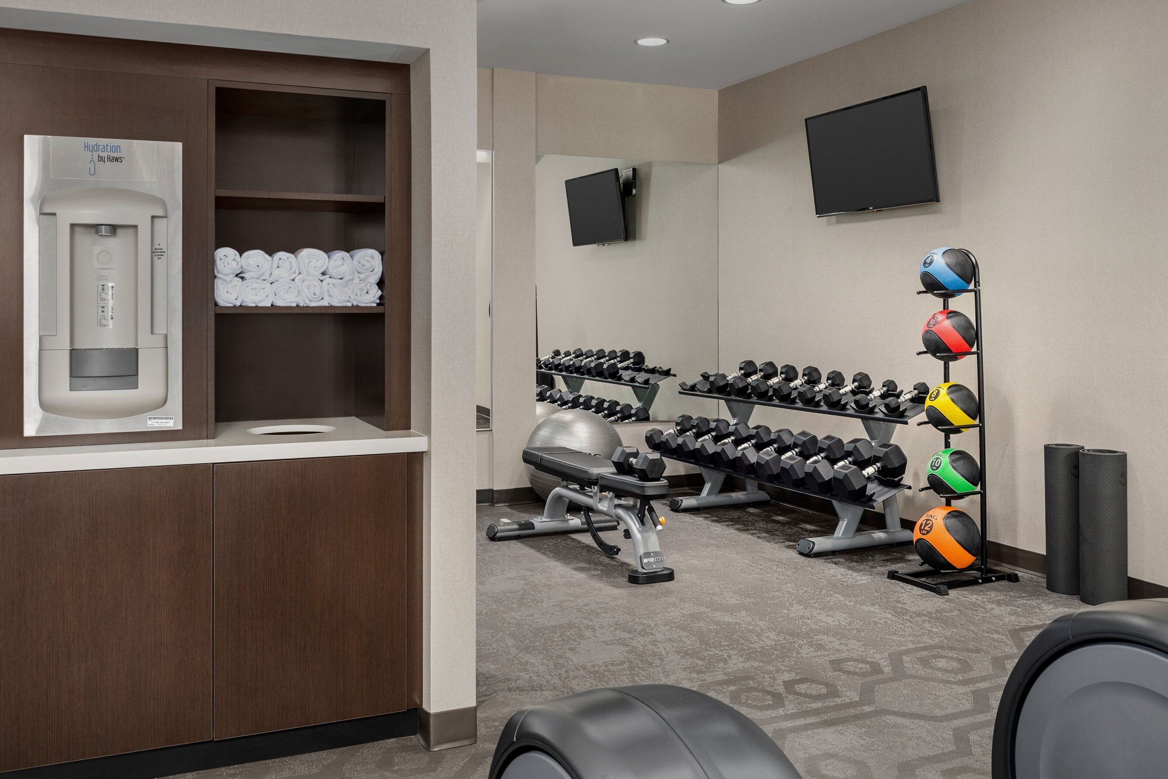 A gym with dumbbells, exercise balls, and a hydration station.