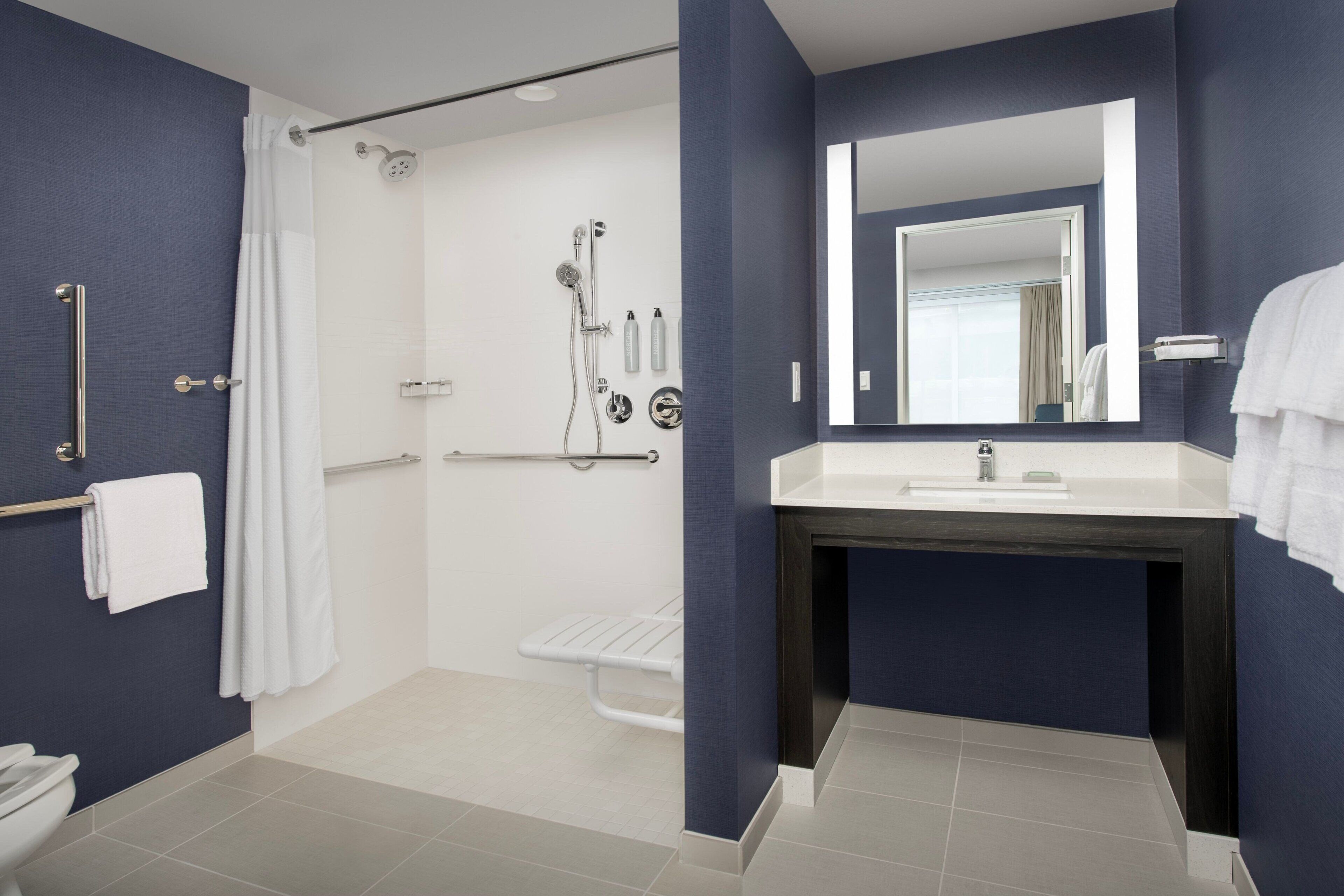 A modern bathroom with a walk-in shower, a white sink, and a dark vanity.
