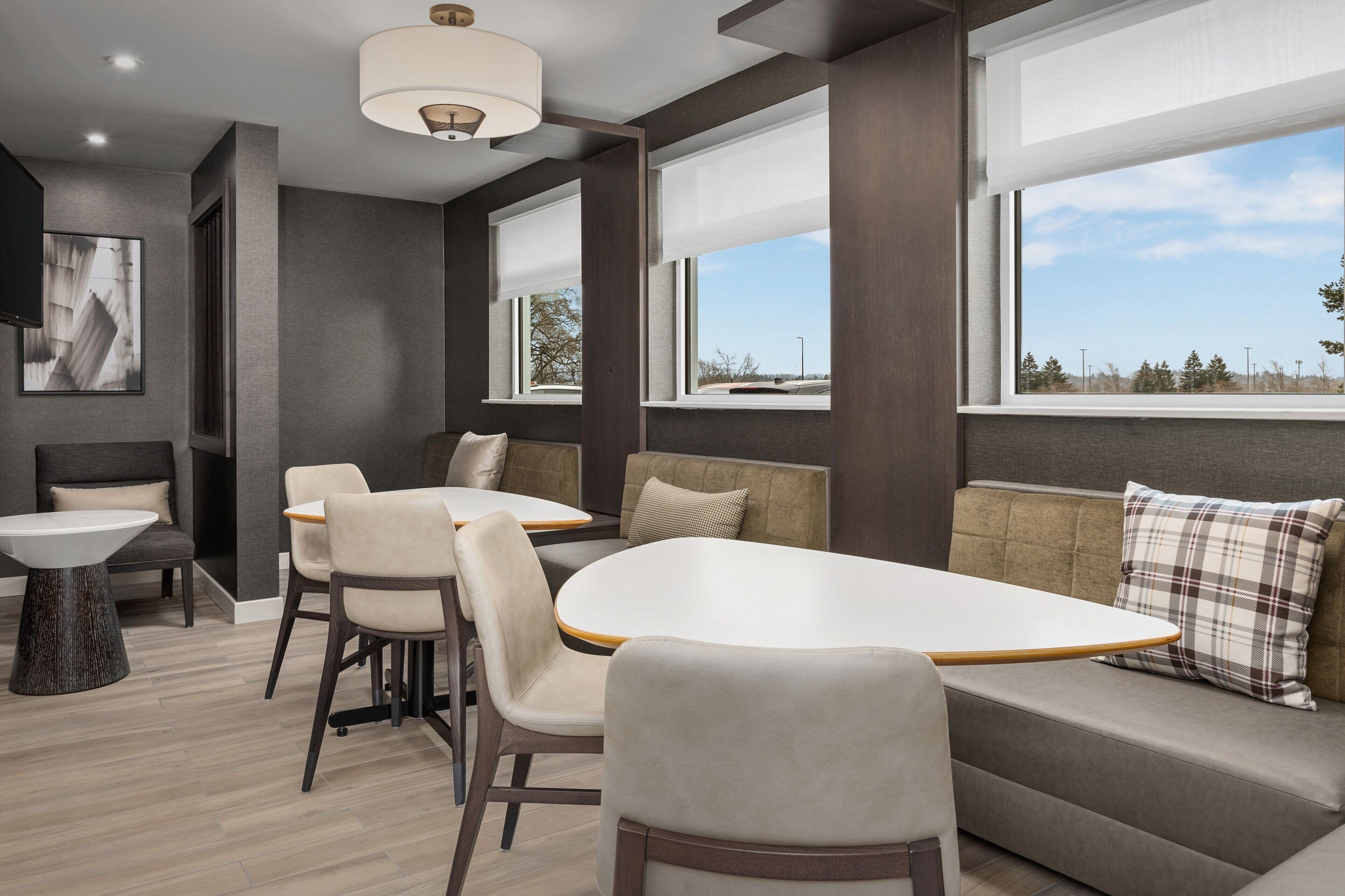 A modern interior with a dining area, seating, and large windows.