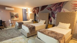 A hotel room with two beds, a desk, a chair, and a large floral mural on the wall. - Basha Hotel & Restaurant (San Pedro Sula)