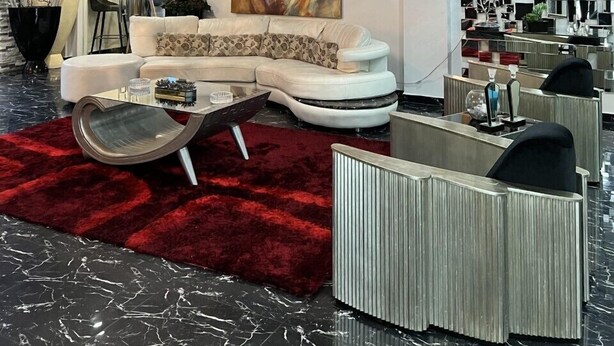 A modern living room with a white sofa, a red rug, and a large abstract painting. - Basha Hotel & Restaurant (San Pedro Sula)