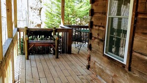 A wooden cabin with a porch, a bench, and a table with chairs. - Hilltop Cabin (Newland)
