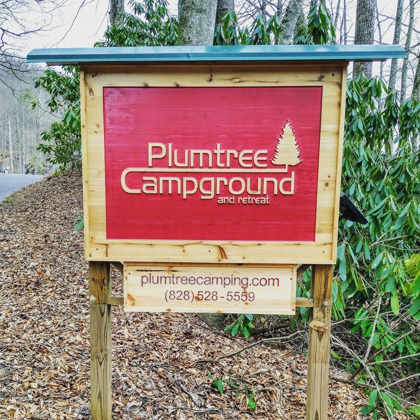 A wooden signboard for Plumtree Campground and retreat with contact information.