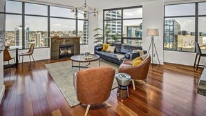 Ein geräumiges Wohnzimmer mit Kamin, Ledersofas und großen Fenstern mit Blick auf die Stadt.