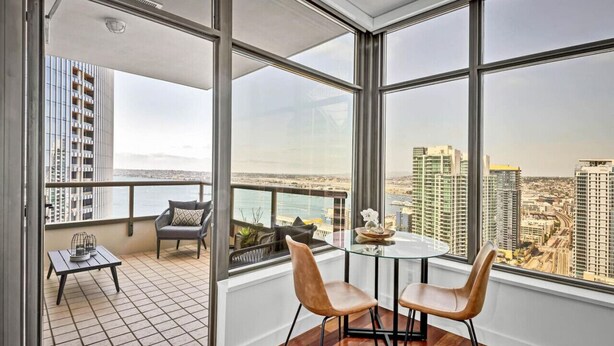 Eine hohe Wohnung mit Balkon, großen Fenstern und Blick auf die Stadt.