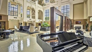 Eine geräumige Lobby mit einem Flügel, bequemen Sitzgelegenheiten und großen Fenstern.