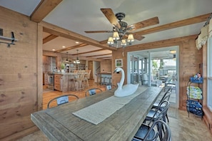 A spacious dining area with a long wooden table, a white swan centerpiece, and a ceiling fan.