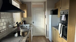 A compact kitchen with a built-in oven, microwave, and sink. - Spacious Detached Bungalow With Ample Parking (Grantham)