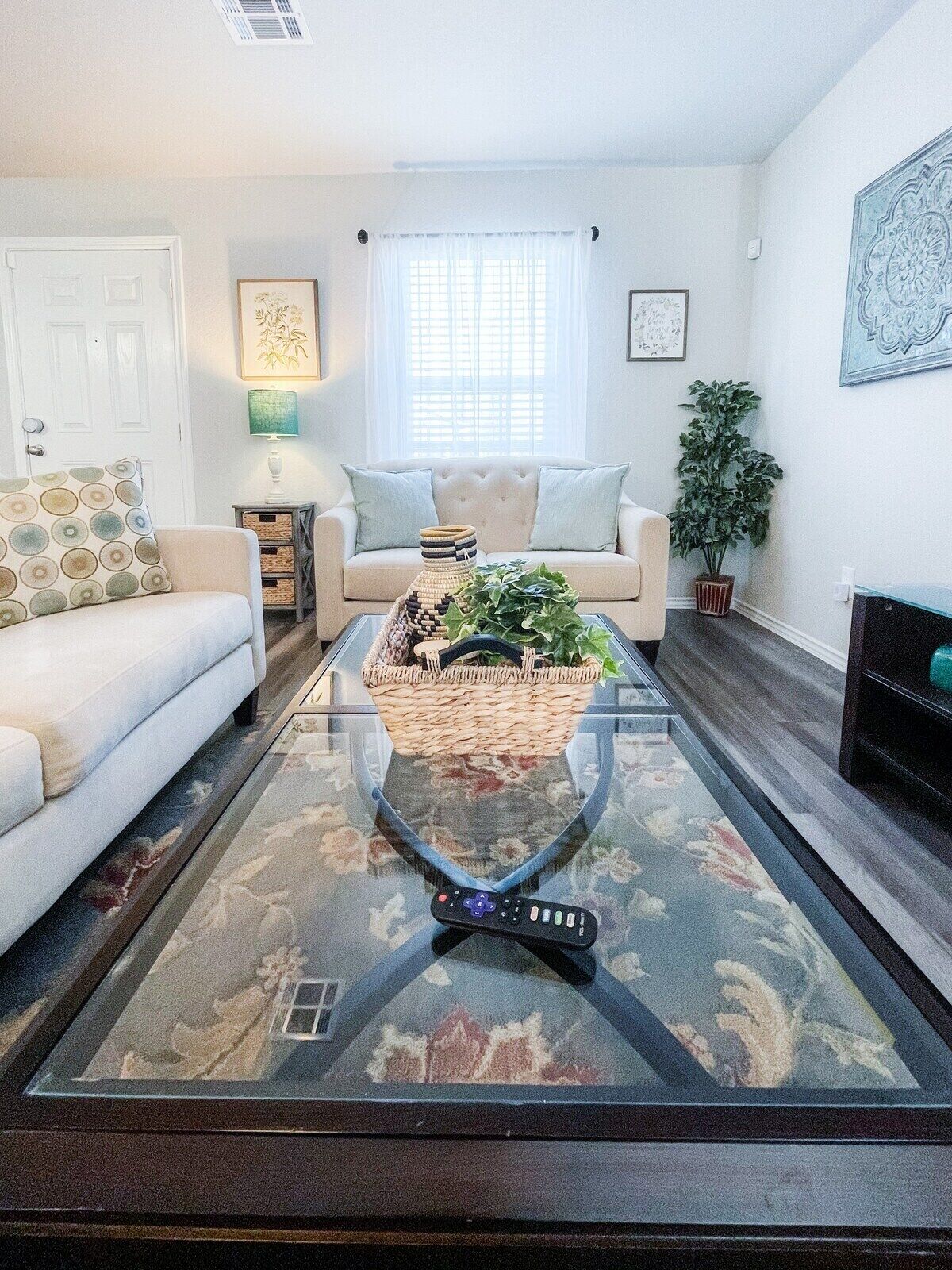 Un salon comprenant un canapé, une table basse avec un panier en osier, une plante en pot et une cheminée.