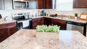 A kitchen with granite countertops, a built-in microwave, a stove, and a dishwasher. - Stylish Family Home  Near Lackland  POOL! (San Antonio)
