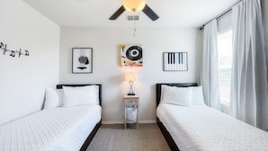 A hotel room with two beds, a ceiling fan, a wall-mounted lamp, and framed pictures. - Stylish Family Home  Near Lackland  POOL! (San Antonio)