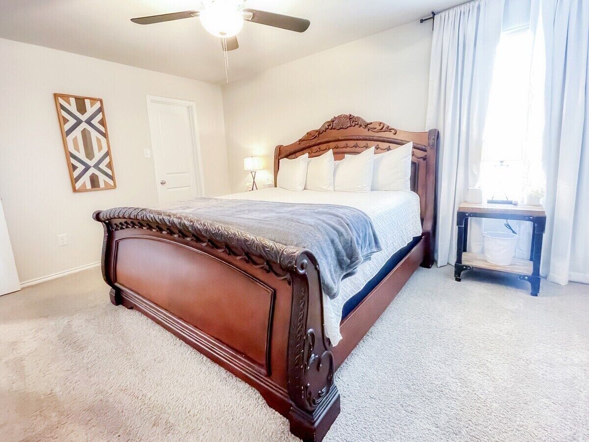 Un dormitorio con cama de madera, ventilador de techo, mesita de noche y lámpara de pared.