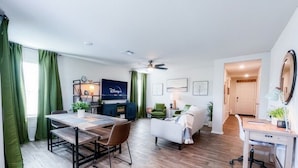 A modern living room with a dining area, a TV, and a desk. - Stylish Family Home  Near Lackland  POOL! (San Antonio)