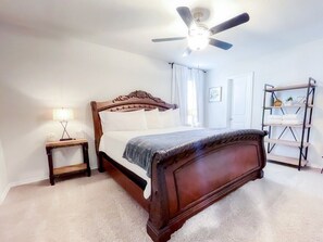 Ein Schlafzimmer mit einem hölzernen Bett, einem Nachttisch, einem Deckenventilator und einem Regal mit Handtüchern.