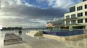A waterfront hotel with a pool, a large cruise ship docked nearby, and a view of the sea. - UNBEATABLE LOCATION IN THE HEART OF DOWNTOWN ORANJESTAD. (Oranjestad)