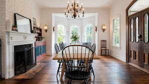 A dining room with a wooden table and chairs, a chandelier, and a fireplace. - Magnolia House estate - family reunions, micro-weddings, retreats. (Hot Springs)
