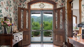 A wooden door with a stained glass window, leading to a balcony with a view of a forested hillside. - Magnolia House estate - family reunions, micro-weddings, retreats. (Hot Springs)