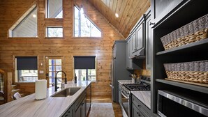 Una cocina moderna con paredes de madera, una isla grande, electrodomésticos de acero inoxidable y cestas tejidas en estantes.