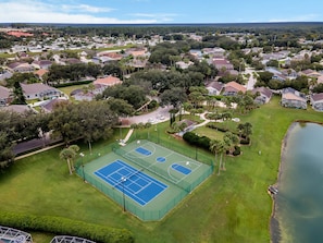 An aerial view of a residential area with a tennis court surrounded by houses and greenery. - Spacious House, Near Disney, 4BDR & 3bath Sleeps up to 10,Game Room+ Heated Pool (Davenport)