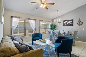 A living room with a sofa, two armchairs, a coffee table, and a dining area with a table and chairs. - Spacious House, Near Disney, 4BDR & 3bath Sleeps up to 10,Game Room+ Heated Pool (Davenport)