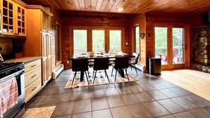 L’intérieur d’un chalet en bois comprend une cuisine, un coin repas et de grandes fenêtres.