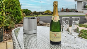 Une bouteille de champagne Comte de Brisand Brut Réserve sur une table, accompagnée de deux verres.