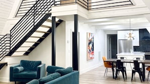 Un loft spacieux avec une mezzanine, un escalier, un coin repas et un salon doté d’un grand canapé.