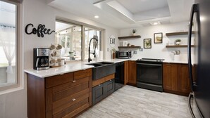 A modern kitchen with wooden cabinets, a built-in oven, a microwave, and a coffee station.